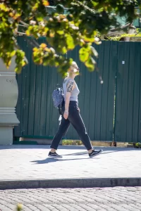 Фотография уличной моды в Одессе: женщина с татуировкой на руке идет по улице, неся рюкзак.