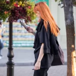 Фотография девушки с татуировкой на руке, идущей по улице. Детализированный рисунок, современный стиль и привлекательный дизайн. Идеально для поиска идей.
