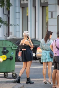 Фотография девушки с татуировкой на руке, стоящей на улице. Детализированный рисунок, современный стиль и привлекательный дизайн. Идеально для поиска идей.