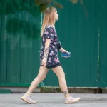 Фото тату на бедре с изображением черепов, украшенных яркими цветами в стиле олдскул. Рисунок выполнен в насыщенных красных, черных и зеленых тонах.