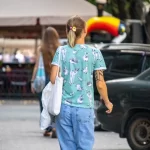 Фото тату на предплечье с изображением множества лесных животных: зайцев, лис, ежей и птиц в мультяшном стиле. Рисунок выполнен в пастельных тонах.