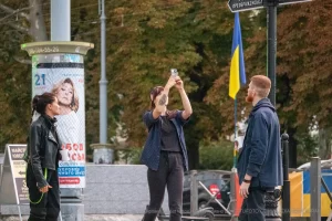 Фотография уличного тату-мастера, делающего татуировку клиенту на улице. Виден процесс нанесения рисунка, мастер с оборудованием.