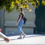 Фотография девушки с татуировкой на руке, держащей смартфон. Рисунок татуировки выполнен в черном цвете и представляет собой сложный узор.