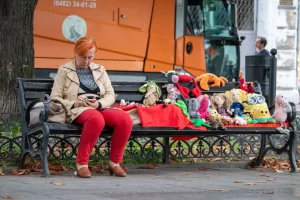 Фото женщины с татуировкой на руке, сидящей на скамейке. Татуировка выполнена в черном цвете и выглядит стильно и элегантно.
