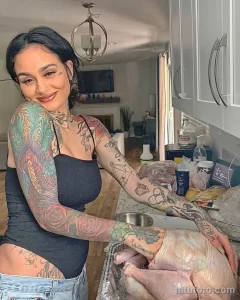 Фотография демонстрирует девушку с впечатляющими татуировками на руках, выполненными в ярких цветах и изображающими разнообразные растения и цветы.