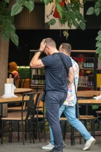 Крупный план татуировки на руке мужчины, выполненной в черном цвете. Виден фрагмент рисунка, напоминающий надпись или узор.