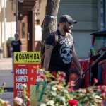 Фото тату черепа с американской символикой на плече мужчины. Черно-белый рисунок татуировки выполнен в стиле олдскул с добавлением звезд и надписей.