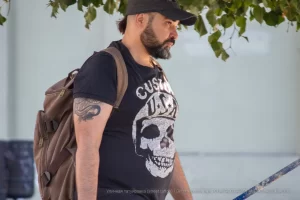 Фото тату черепа с американской символикой на плече мужчины. Черно-белый рисунок татуировки выполнен в стиле олдскул с добавлением звезд и надписей.