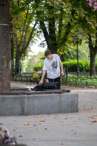 Фото татуировок на руках мужчины, сидящего на скамейке. Изображены абстрактные узоры и рисунок птицы.