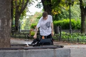 Фото татуировок на руках мужчины, сидящего на скамейке. Изображены абстрактные узоры и рисунок птицы.