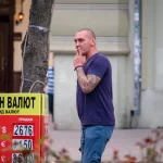 Фотография мужчины с татуировкой на руке, идущего по улице. Татуировка выполнена в стиле традиционной японской татуировки с изображением дракона и цветов.