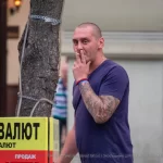 Фото тату на руке мужчины, выполненное в стиле традиционной японской татуировки, с изображением дракона и цветов. Уличная фотография.