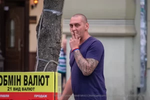 Фото тату на руке мужчины, выполненное в стиле традиционной японской татуировки, с изображением дракона и цветов. Уличная фотография.