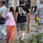 Фото мужчины с татуировками: яркий рисунок гориллы на спине, реалистичный воин на ноге. Уличная фотография, демонстрирующая контраст стилей.