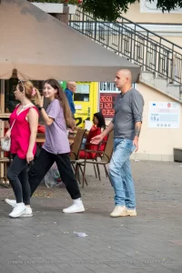 Фотография мужчины с татуировкой на предплечье: изображение летящих птиц, выполненное в черном цвете. Уличная съемка, демонстрирующая тату в повседневной жизни.