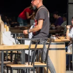 Фото тату на руке мужчины: яркий рисунок в стиле Old School с черепом, розами и символикой Harley Davidson. Детальное изображение для вдохновения.