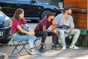 Фотография группы людей, отдыхающих на улице. У одного из них видна татуировка на руке.