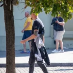 Фотография мужчины с татуировкой на руке, идущего по улице. Татуировка частично видна из-под рукава.