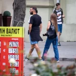 Фото татуировки на ноге мужчины, идущего по улице. Виден детализированный рисунок, выполненный в реалистичном стиле, с изображением мифологического существа.