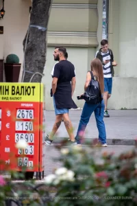 Фото татуировки на ноге мужчины, идущего по улице. Виден детализированный рисунок, выполненный в реалистичном стиле, с изображением мифологического существа.