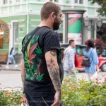 Фото татуировки на спине мужчины: листья марихуаны, черепа и другие элементы. Уличная фотография.