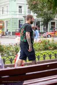 Фото татуировки на руке и спине мужчины: листья марихуаны, черепа и другие элементы. Уличная фотография.