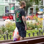 Фото татуировки на руке и спине мужчины: листья марихуаны, черепа и другие элементы. Уличная фотография.