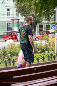 Фото татуировки на руке и спине мужчины: листья марихуаны, черепа и другие элементы. Уличная фотография.