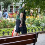 Фото татуировки на спине мужчины: листья марихуаны, черепа и другие элементы. Уличная фотография.