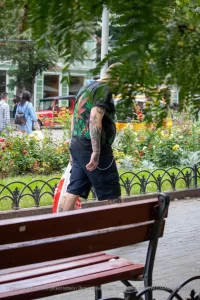 Фото татуировки на спине мужчины: листья марихуаны, черепа и другие элементы. Уличная фотография.