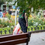 Фото татуировки на спине мужчины: листья марихуаны, черепа и другие элементы. Уличная фотография.