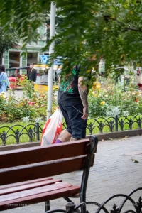 Фото татуировки на спине мужчины: листья марихуаны, черепа и другие элементы. Уличная фотография.