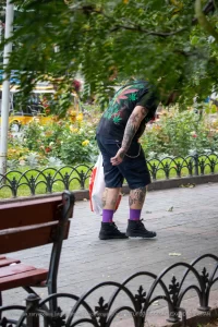 Фото татуировки на спине мужчины: листья марихуаны, черепа и другие элементы. Уличная фотография.