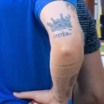 Фото татуировки на руке с изображением серой короны и надписью 'freedom'. Минималистичный рисунок татуировки, выполненный опытным мастером.