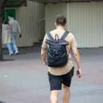 Фото татуировки на руке мужчины, изображающей ворона и крест. Татуировка выполнена в черном цвете, с использованием четких линий и теней. Уличная фотография.