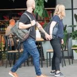 Фото тату на руке мужчины в стиле олдскул: корабль, роза, якорь, морские волны. Девушка держит мужчину за руку. Красочный рисунок татуировки.