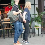 Фото тату на руке мужчины в стиле олдскул: корабль, роза, якорь, морские волны. Девушка держит мужчину за руку. Красочный рисунок татуировки.