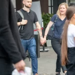 Фото тату на руке мужчины в стиле олдскул: корабль, роза, якорь, морские волны. Девушка держит мужчину за руку. Красочный рисунок татуировки.