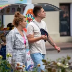 Фото тату на руке молодого человека, идущего с девушкой по улице. Рукав татуировок выполнен в стиле графика с элементами черной работы.