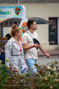 Фото тату на руке молодого человека, идущего с девушкой по улице. Рукав татуировок выполнен в стиле графика с элементами черной работы.