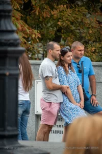 Фото мужчины с татуировкой спирали на руке, одетого в серую футболку. Татуировка выполнена в черном цвете и имеет минималистичный дизайн.