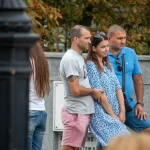 Фото мужчины с татуировкой спирали на руке, стоящего рядом с женщиной и другим мужчиной. Татуировка выполнена в черном цвете.
