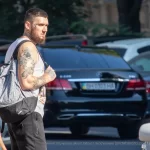 Фото тату на руке мужчины: детализированный черно-серый рисунок с японскими мотивами, карпами кои и цветами, выполненный в стиле ирреализм.