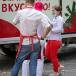Фото тату на руке мужчины: детализированный рукав с изображением цветов, листьев и насекомых. Эскиз татуировки выполнен в реалистичном стиле с использованием черных и серых оттенков.