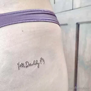 Фото тату: небольшая татуировка с надписью "Yes, Daddy" на бедре девушки, выполненная тонким шрифтом.