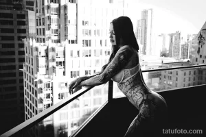 Фото тату: черно-белая татуировка, покрывающая бок, спину и руку девушки. Изящные узоры и цветочные мотивы создают эффектный образ.
