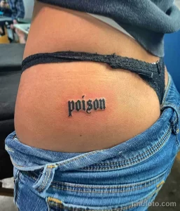 Фото тату на бедре с надписью 'poison' готическим шрифтом. Простой и лаконичный рисунок татуировки.