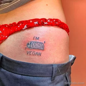 Фото тату: небольшая татуировка с надписью 'I'm Vegan' и изображением авокадо на бедре.