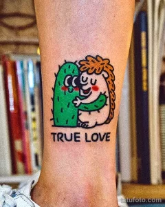 Фото татуировки ежика, обнимающего кактус, с надписью "TRUE LOVE". Рисунок выполнен в ярких цветах с использованием простых форм.