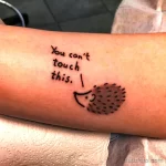 Фото тату ежа с надписью "You can't touch this". Черно-белый рисунок татуировки в минималистичном стиле. Забавный и оригинальный выбор для любителей музыки.